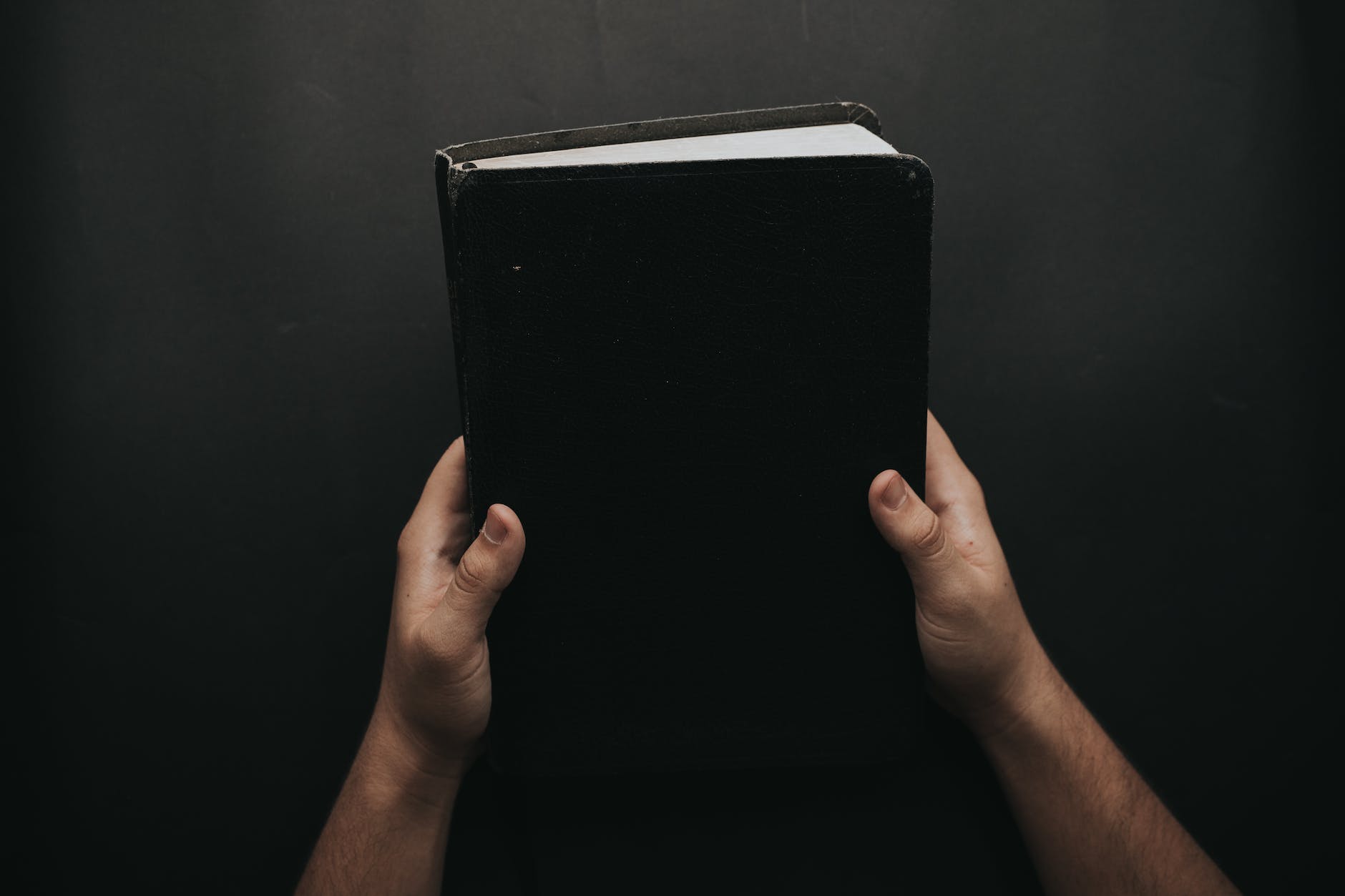 person holding black cover bible