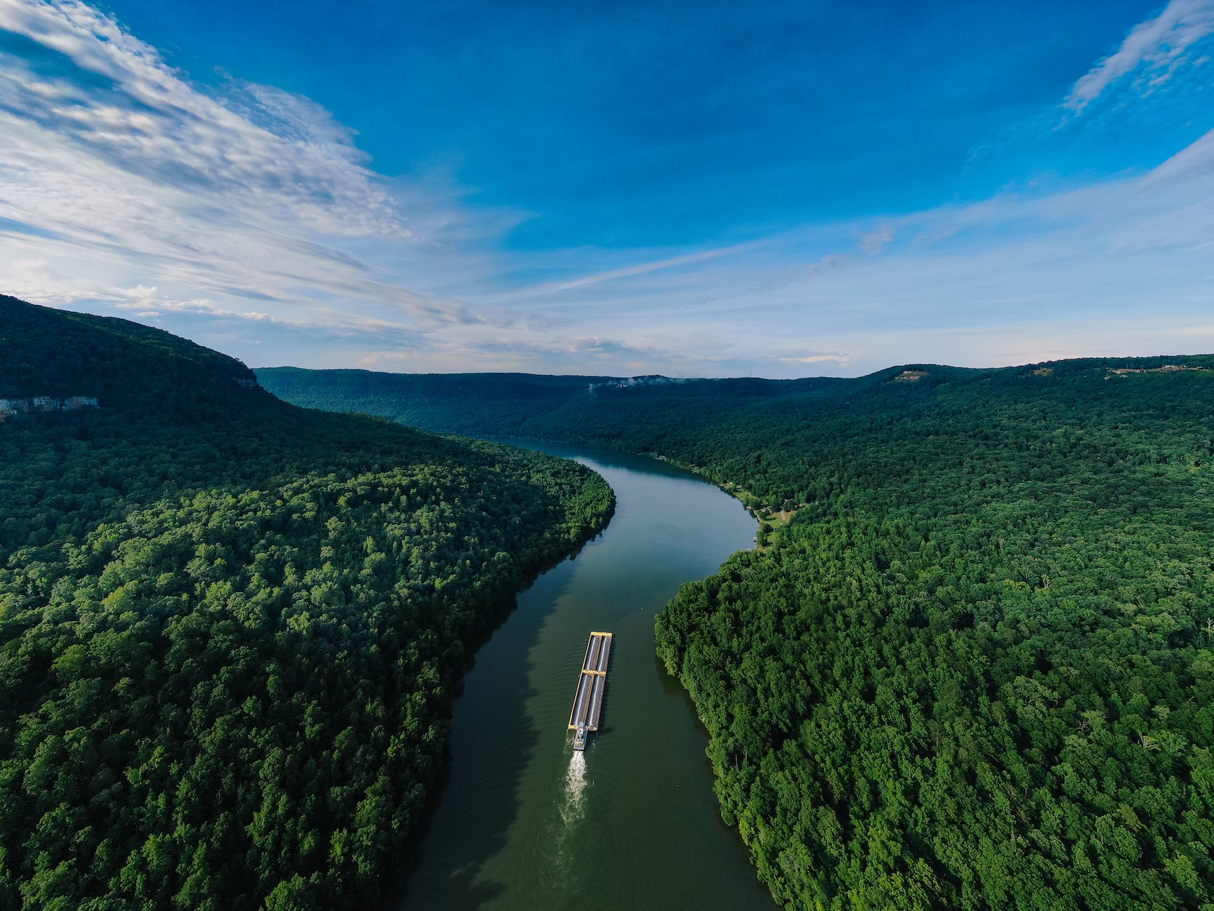 aerial photography of a boat on a waterway in the middle of forest