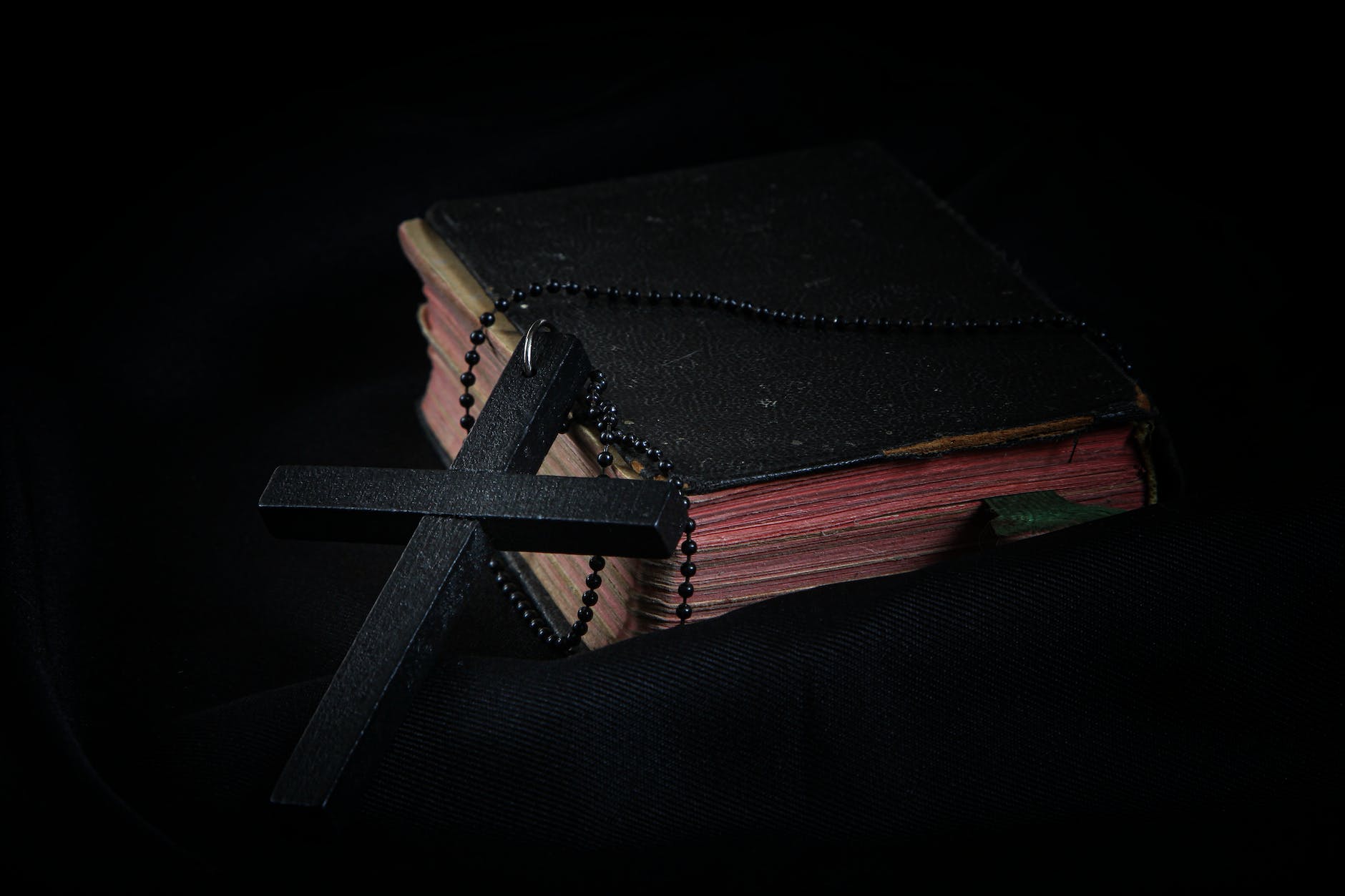 black cross leaning on black hardcover bible